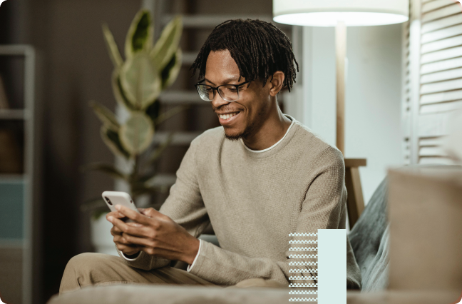 Happy black guy with a nude jacket holding his mobile